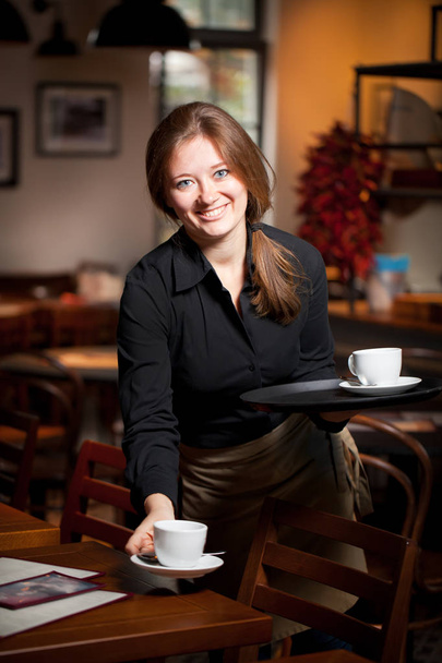 Portrait of waitress holding tray of coffee cups in cafe - Zdjęcie, obraz
