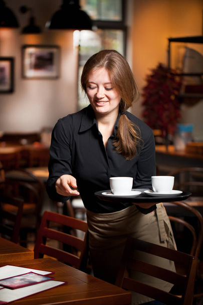 Portrait of waitress holding tray of coffee cups in cafe - Foto, Imagem