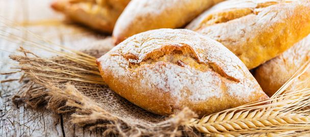Different kinds of fresh bread on wooden table. Isolated assortment of bread on brown background. - Photo, Image