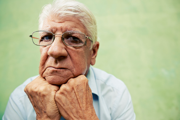 Portrait de vieil homme sérieux regardant la caméra avec les mains sur le menton
 - Photo, image