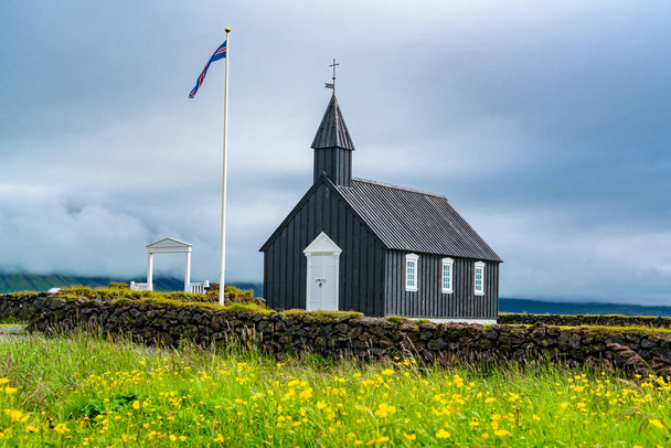 Buoakirja Black Church of Budir with the field of flowers in summer rainy day at the western region of Iceland - 写真・画像