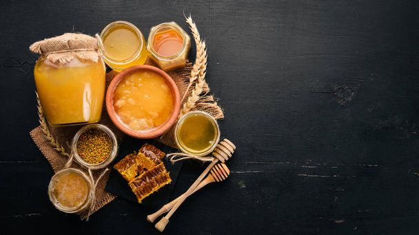 A set of honey and bee products. Honey in honeycomb. On a black wooden background. Free space for text. Top view. - Valokuva, kuva
