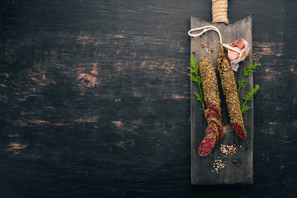 Sausage Fuet. Salami with spices. On a black background. Top view. Free space for your text. - Zdjęcie, obraz