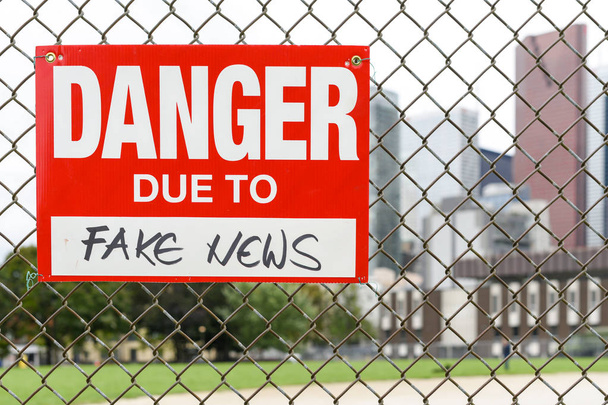 Assine o perigo devido a notícias falsas anexadas à cerca na frente da cidade
 - Foto, Imagem