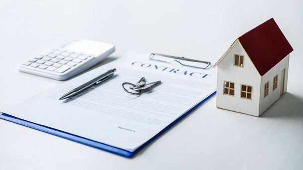 House model, calculator and house key lying on real estate contract, home loan and investment concept. - Fotoğraf, Görsel