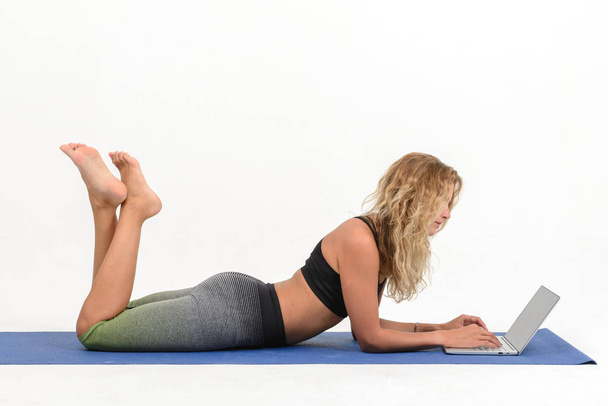 Красивая молодая женщина делает йогу с ноутбуком на белом фоне
 - Фото, изображение