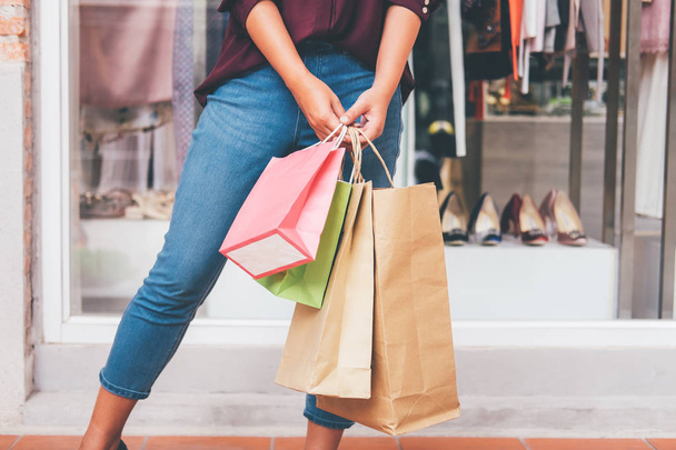 Consumismo, concepto de estilo de vida de compras, mujer joven de pie y sosteniendo bolsas de compras coloridas disfrutando en las compras
. - Foto, imagen
