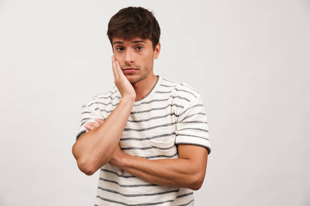 Photo of confused handsome man standing isolated over white background wall. - Фото, изображение