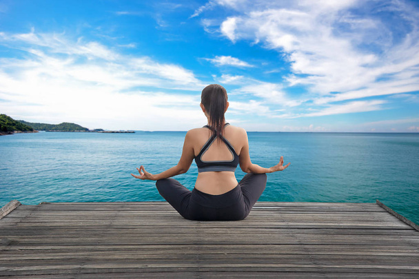 Healthy woman lifestyle balanced yoga practicing meditate and energy on the bridge in morning the seashore. Healthy Concept. - Φωτογραφία, εικόνα