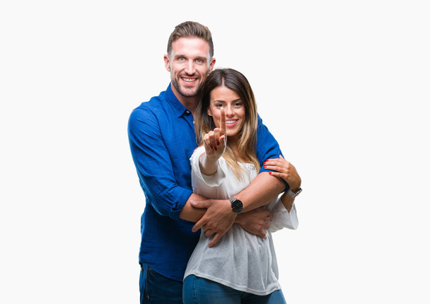 Young couple in love over isolated background showing and pointing up with finger number one while smiling confident and happy. - Photo, image