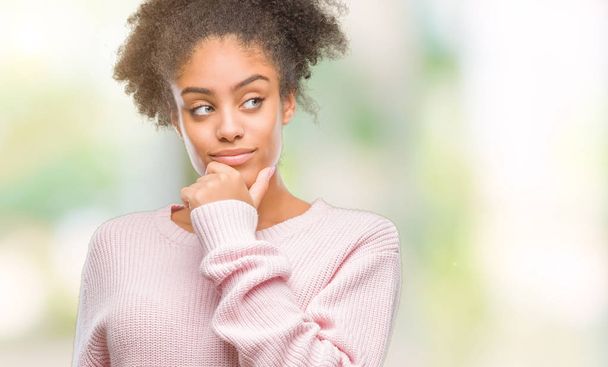 Young afro american woman wearing winter sweater over isolated background looking confident at the camera with smile with crossed arms and hand raised on chin. Thinking positive. - Foto, immagini