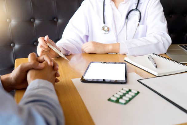 Arzt kümmert sich, Patient hört aufmerksam einem männlichen Arzt zu, der in einem Beratungsgespräch die Symptome des Patienten erklärt, mit weißem Tablettenbildschirm mit Ausschnitt - Foto, Bild
