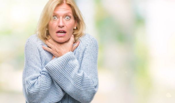 Middle age blonde woman wearing winter sweater over isolated background shouting and suffocate because painful strangle. Health problem. Asphyxiate and suicide concept. - Photo, Image