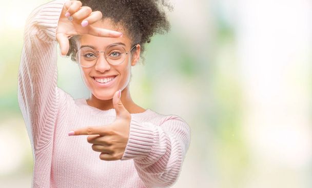 Mujer afroamericana joven con gafas sobre fondo aislado sonriendo haciendo montura con manos y dedos con cara feliz. Concepto de creatividad y fotografía
. - Foto, imagen