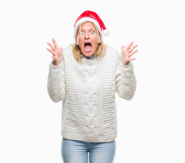 Blonde Frau mittleren Alters mit Weihnachtsmütze vor isoliertem Hintergrund feiert verrückt und erstaunt über den Erfolg mit erhobenen Armen und offenen Augen, die aufgeregt schreien. Siegerkonzept - Foto, Bild