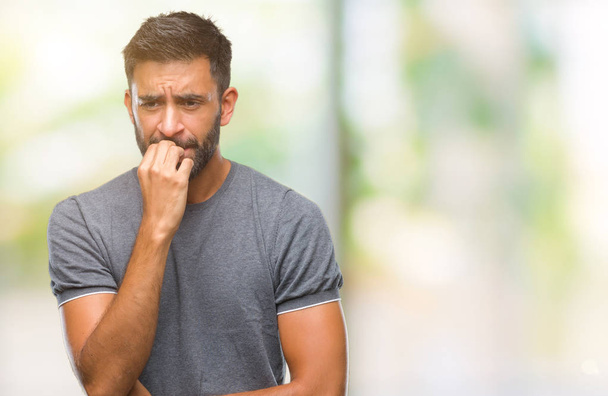 Volwassen Spaanse man over geïsoleerde achtergrond op zoek gestresst en nerveus met handen op mond nagels te bijten. Angst probleem. - Foto, afbeelding