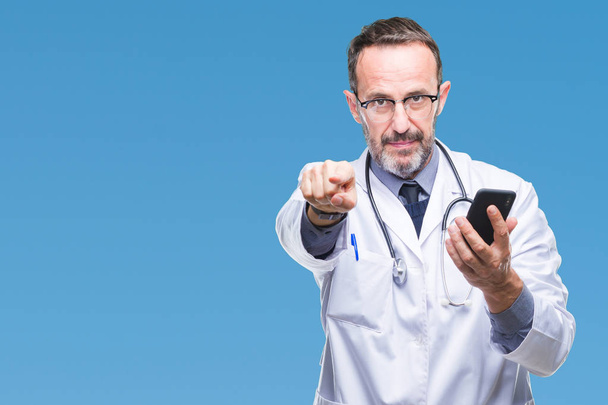 Старший седовласый врач средних лет пишет смс с помощью смартфона на изолированном фоне, указывая пальцем на камеру и на вас, знак руки, позитивный и уверенный жест спереди
 - Фото, изображение