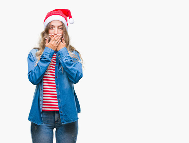 Beautiful young blonde woman wearing christmas hat over isolated background shocked covering mouth with hands for mistake. Secret concept. - Foto, Imagem
