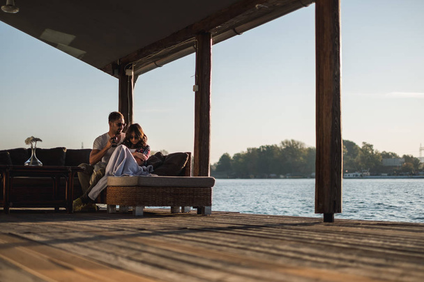 Couple ne parlant pas assis au bord de la rivière au coucher du soleil. Belle journée d'automne
 - Photo, image