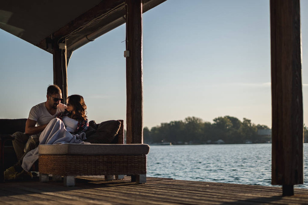 Серьёзная пара, обнимающаяся на закате у реки. Прекрасный осенний день
 - Фото, изображение