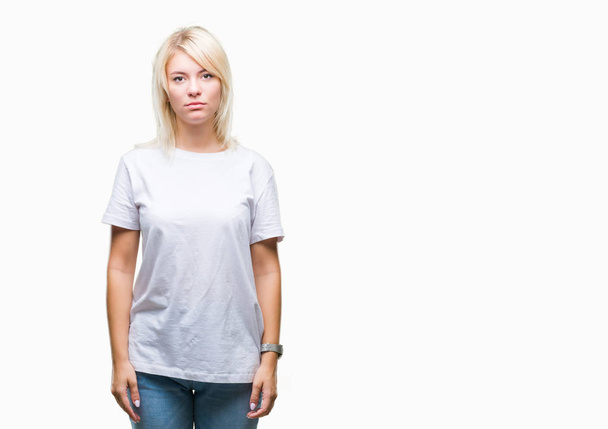 Jovem mulher loira bonita vestindo t-shirt branca sobre fundo isolado com expressão séria no rosto. Simples e natural olhando para a câmera
. - Foto, Imagem