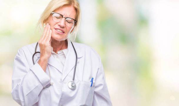Middle age blonde doctor woman over isolated background touching mouth with hand with painful expression because of toothache or dental illness on teeth. Dentist concept. - Photo, Image