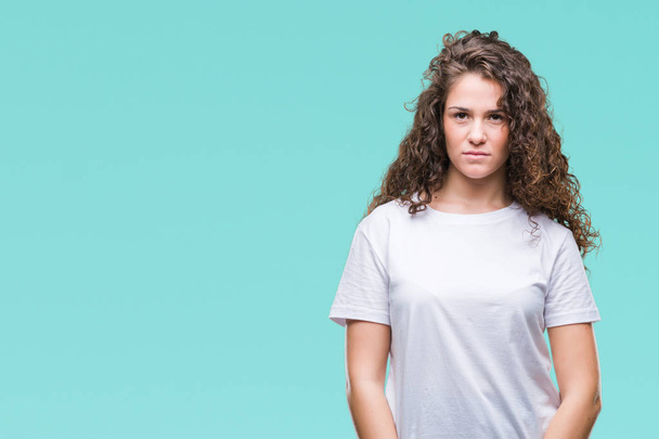 Beautiful brunette curly hair young girl wearing casual t-shirt over isolated background with serious expression on face. Simple and natural looking at the camera. - Valokuva, kuva