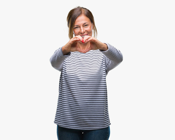 Keski-ikäinen vanhempi latino nainen yli eristetty tausta hymyilee rakkaudessa osoittaa sydämen symboli ja muoto käsin. Romanttinen käsite
. - Valokuva, kuva