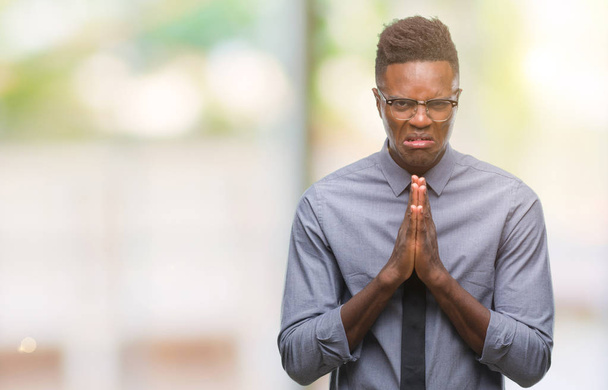 Молодий афроамериканець бізнесменом над ізольованих фону, жебрацтво і молитися руками разом з вираз надії на обличчя дуже емоційний і стурбовані. Просимо вибачення. Концепція релігії. - Фото, зображення