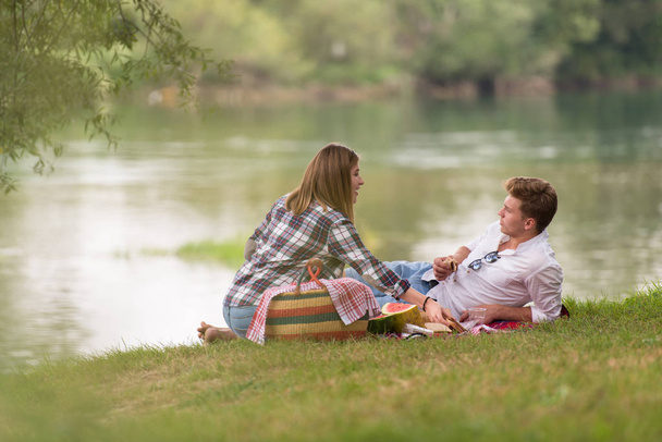 Couple in love enjoying picnic time drink and food in beautiful nature on the river bank - Фото, зображення