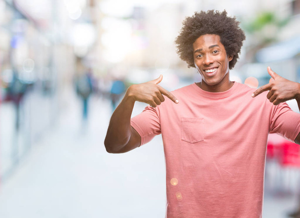 Afro american mężczyzna na białym tle patrząc pewny siebie z uśmiechem na twarzy, wskazując siebie palcami, dumny i szczęśliwy. - Zdjęcie, obraz