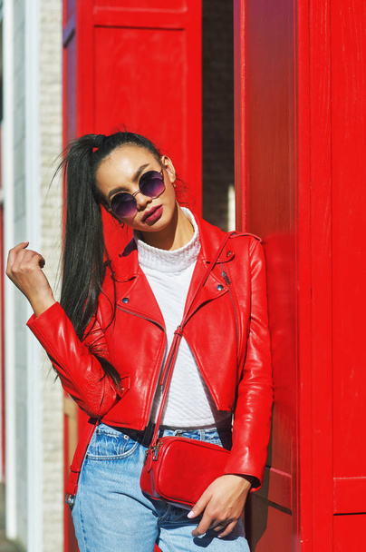 Портрет молодой красивой женщины на городской улице. Модель одета в стильную кожаную куртку и джинсы
 - Фото, изображение
