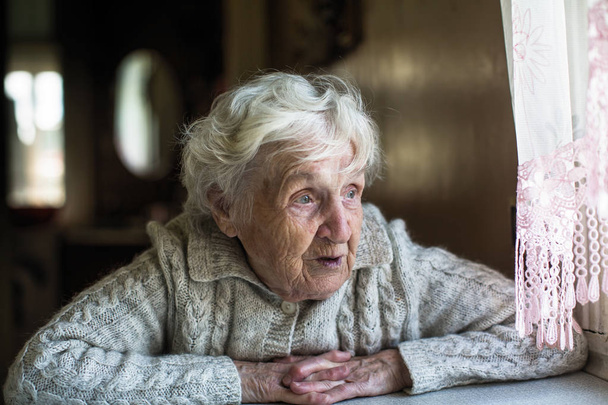 grauhaarige ältere Frau schaut aus dem Fenster. - Foto, Bild