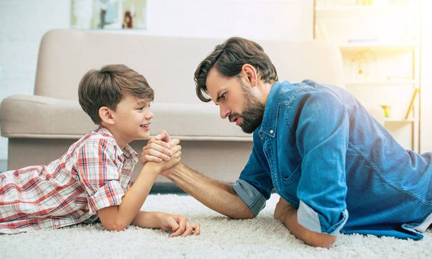 Junger lächelnder Vater spielt mit Sohn zu Hause - Foto, Bild