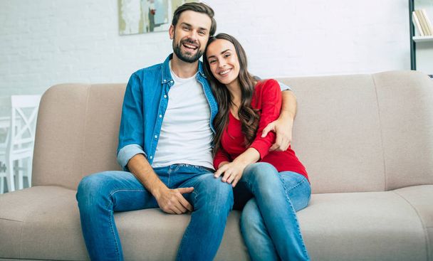 Young happy family sitting on couch in light living room - Photo, Image