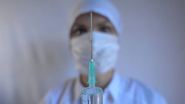 Close-up shot of syringe during injection, drug addiction problem, aids epidemic, vaccination. Medicine liquid delivering to patient body, hospital treatment, health care system, clinic therapy - Photo, Image