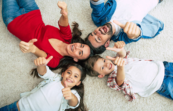 Top view of happy family lying on floor in circle  - Fotografie, Obrázek