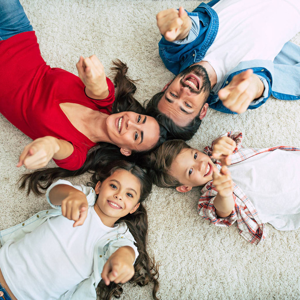 Top view of happy family lying on floor in circle  - Фото, зображення