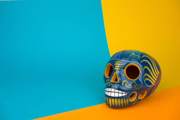 Creative and minimal Day of the Dead or Halloween layout. Skull on blue and orange paper background. Flat lay front view. Copy space. - Zdjęcie, obraz