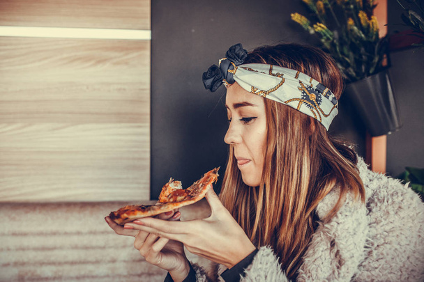 Beautiful happy young woman  eating a slice of pizza in the restaurant - Zdjęcie, obraz