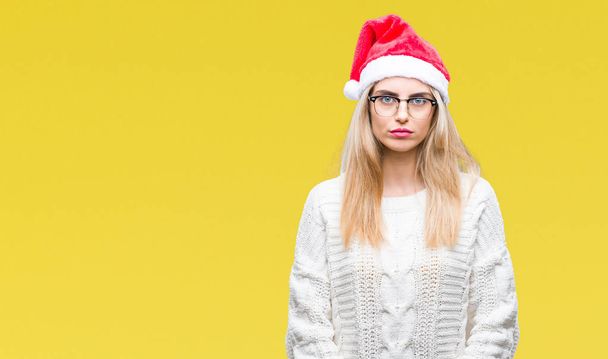 Nuori kaunis blondi nainen yllään joulu hattu yli eristetty tausta vakava ilme kasvot. Yksinkertainen ja luonnollinen kameraan katsominen
. - Valokuva, kuva