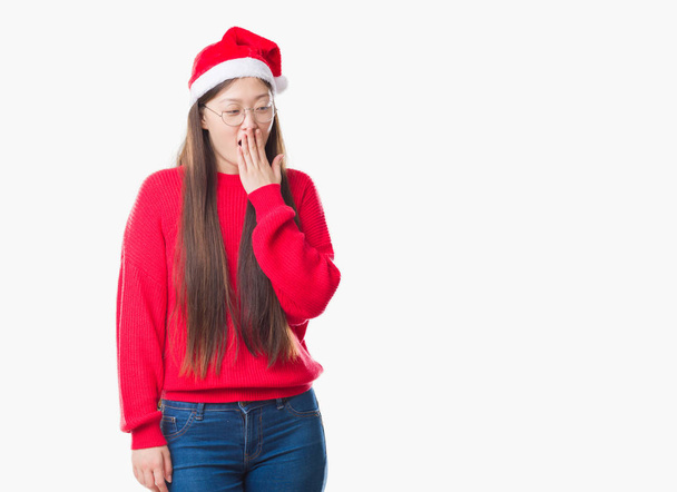 Jovem chinesa sobre fundo isolado vestindo chapéu de Natal entediado bocejo cansado cobrindo boca com a mão. Inquieto e sonolência
. - Foto, Imagem