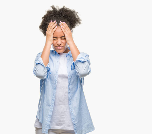 Mujer afroamericana joven sobre fondo aislado que sufre de dolor de cabeza desesperada y estresada porque el dolor y la migraña. Manos en la cabeza
. - Foto, imagen