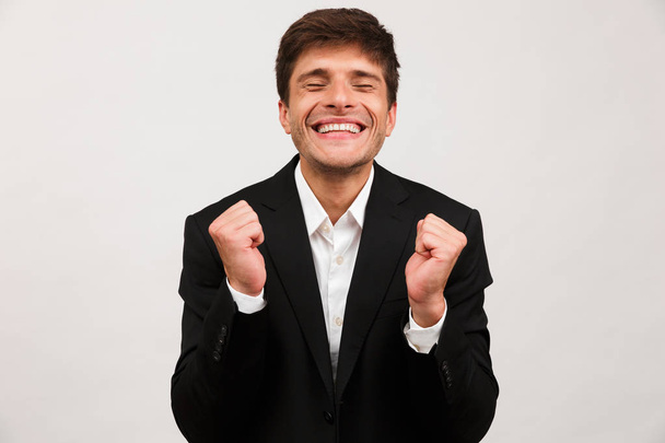 Image of young businessman standing isolated over white background wall make winner gesture. - Foto, Bild