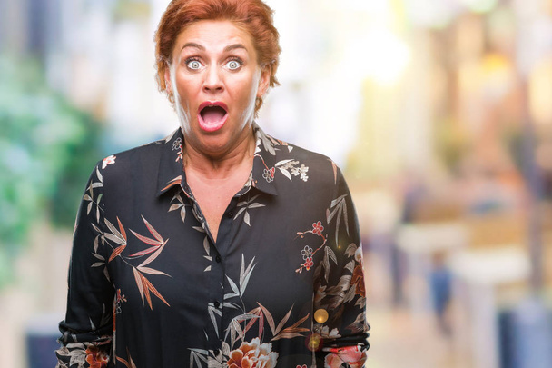 Atrractive senior caucasian redhead woman over isolated background afraid and shocked with surprise expression, fear and excited face. - Photo, Image