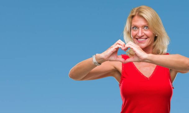 Middle age blonde woman over isolated background smiling in love showing heart symbol and shape with hands. Romantic concept. - Photo, Image