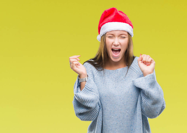 Nuori kaunis valkoihoinen nainen yllään joulu hattu yli eristetty tausta juhlii hullu ja hullu menestystä kädet nostetaan ja suljetut silmät huutaa innoissaan. Voittajan käsite
 - Valokuva, kuva