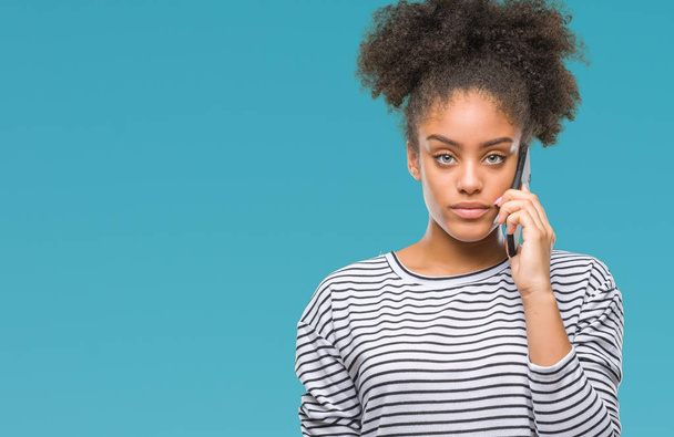 Mujer afroamericana joven hablando por teléfono sobre un fondo aislado con una expresión segura en la cara inteligente pensando en serio
 - Foto, imagen
