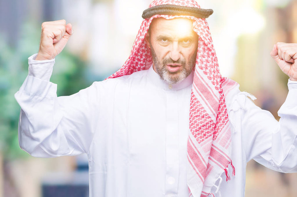 Ανώτερος άνθρωπος Αραβικά φορώντας keffiyeh πέρα από το απομονωμένο υπόβαθρο δείχνει όπλα μύες χαμογελώντας υπερήφανος. Γυμναστήριο έννοια. - Φωτογραφία, εικόνα
