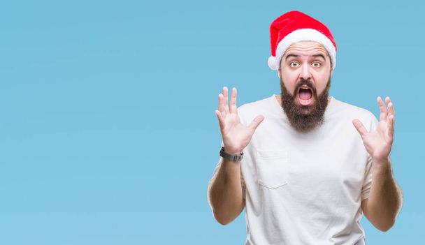 若い白人ヒップ男上クリスマスの帽子をかぶっては、背景を祝う怒って叫んで調達とクローズの目が興奮して腕を成功のために狂気を分離しました。勝者の概念 - 写真・画像